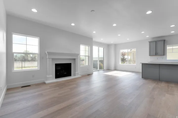 Open-concept living space featuring wood-finish flooring, recessed lighting, and a white mantle fireplace