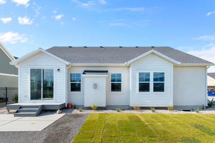 Rear exterior featuring white horizontal siding, a sliding glass door leading to a deck, and multiple windows