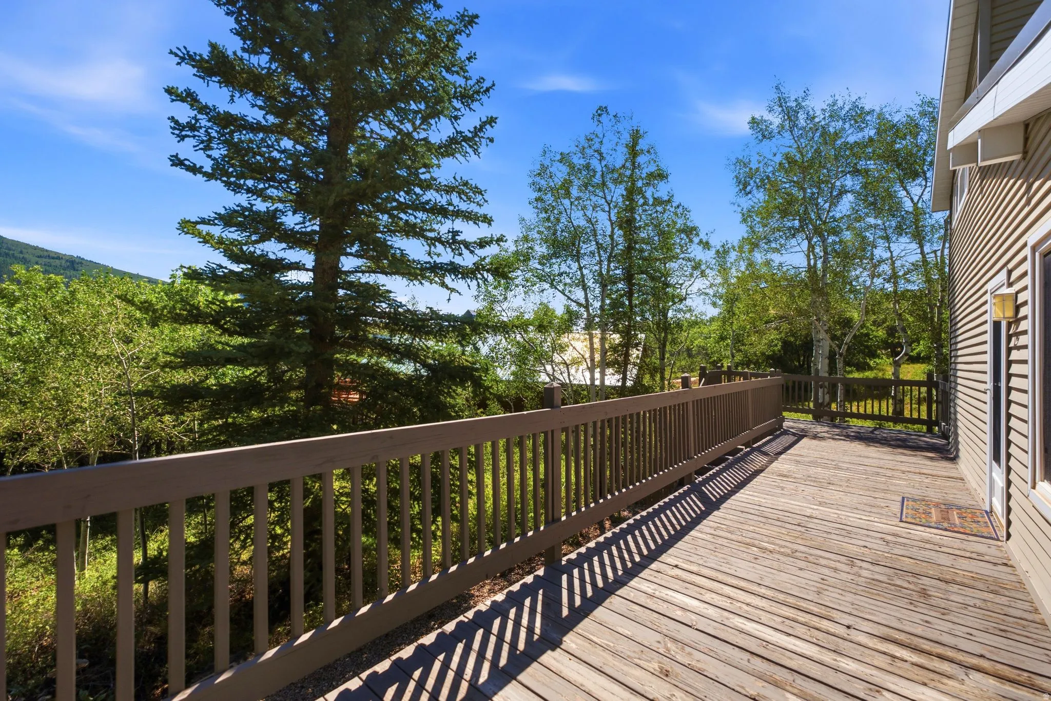 Expansive outdoor wood deck with a full railing and exterior wall siding