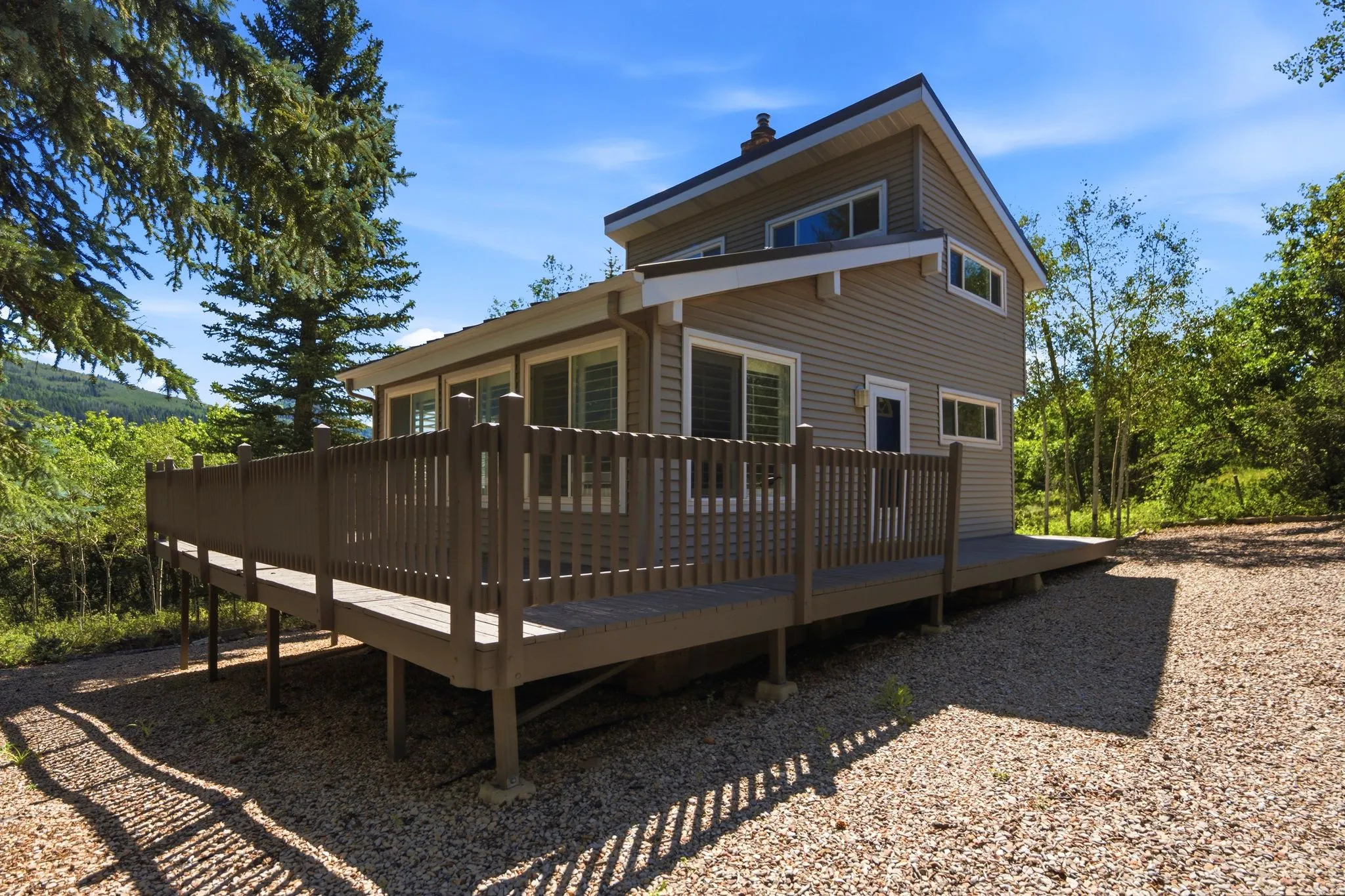 Elevated wood-finish deck surrounding a two-story residence with horizontal siding
