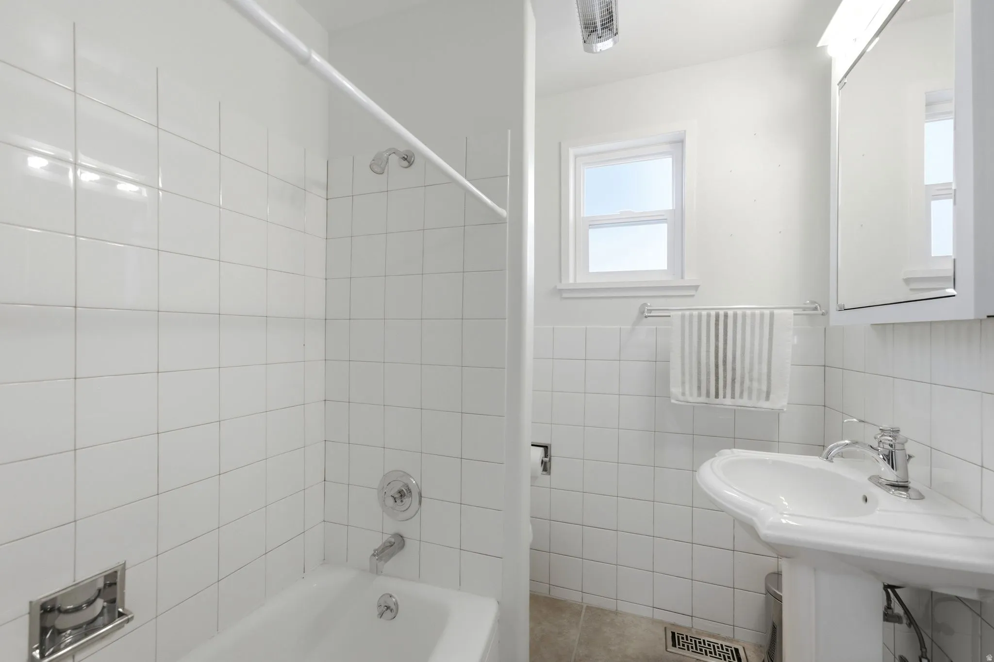 Bathroom featuring a pedestal sink with chrome fixtures, a mirrored medicine cabinet, and a window for natural light