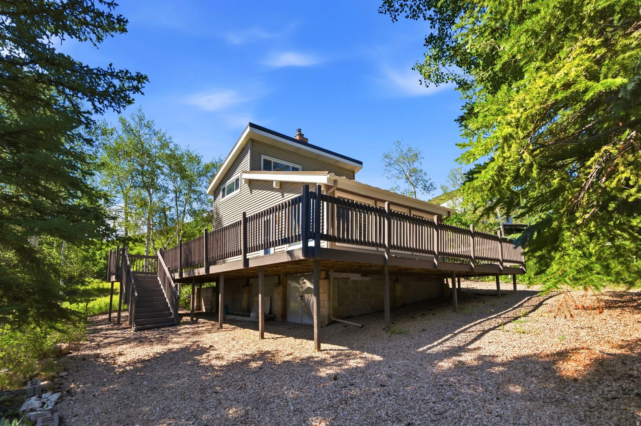 Exterior featuring a spacious elevated deck with dark railings, horizontal siding, and a gabled roofline