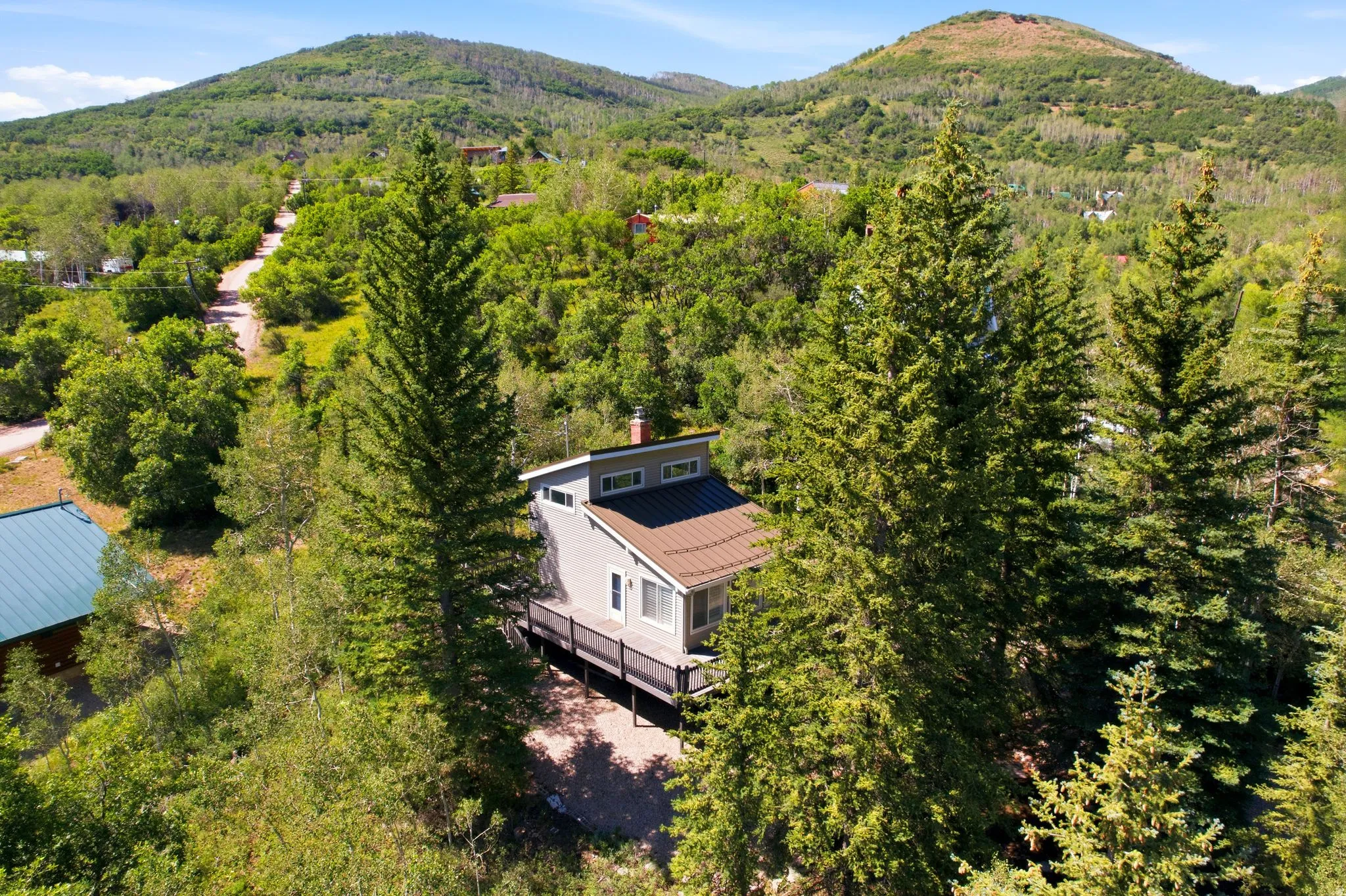 Contemporary home with a brown metal roof, light-colored siding, and a spacious deck