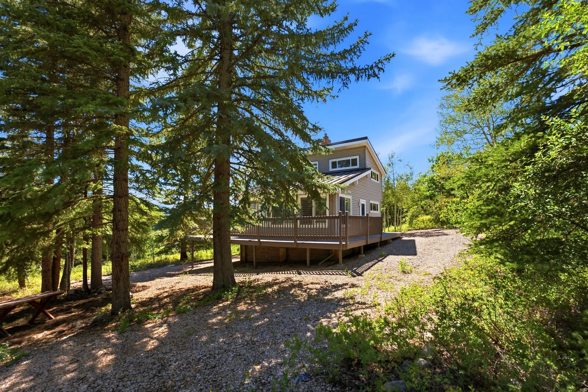Modern residence featuring a neutral-toned exterior, a spacious elevated wood deck, and a dark shingle roof