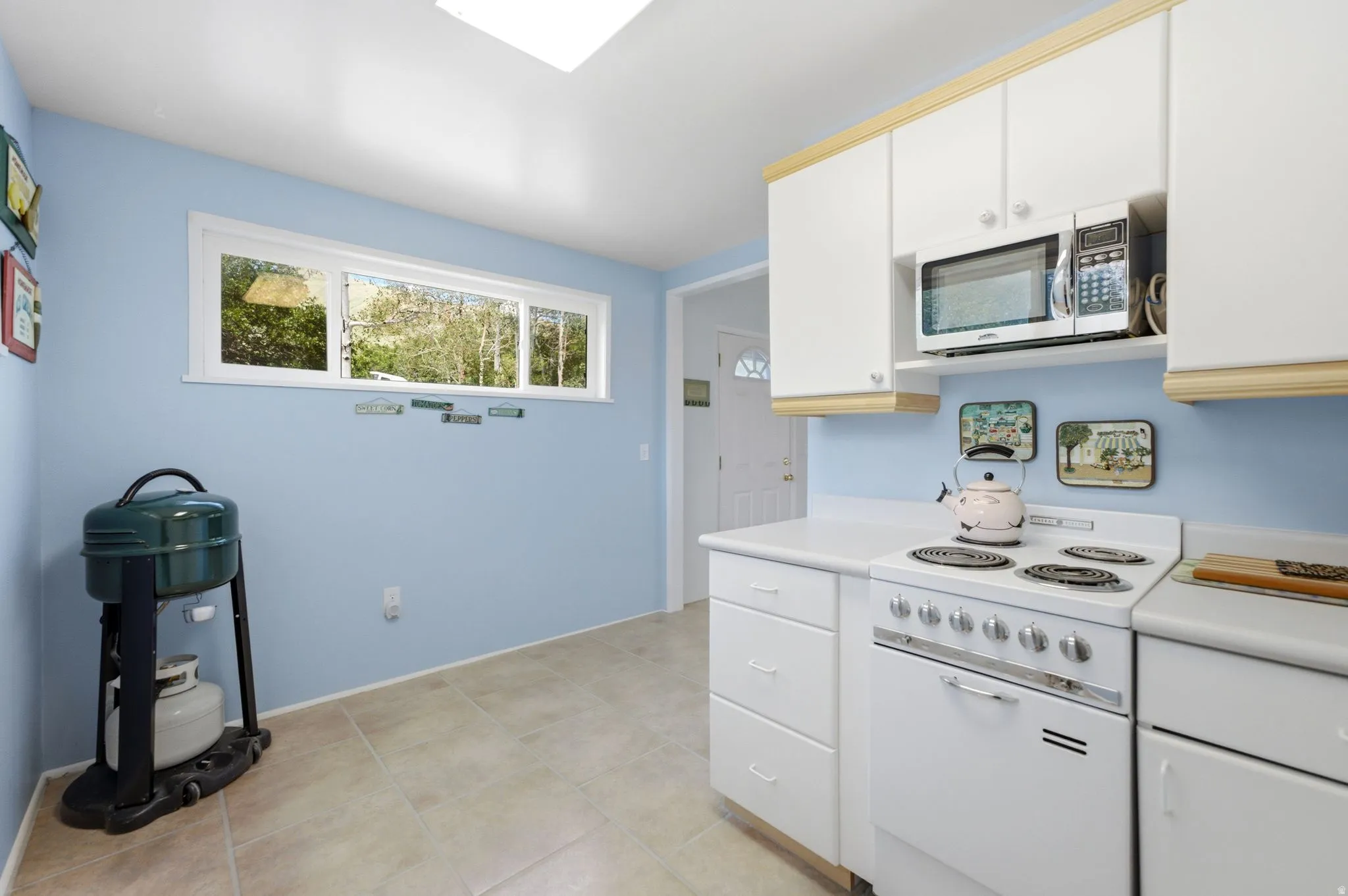 Kitchen featuring white cabinetry, white countertops, a built-in microwave, and a white oven/range
