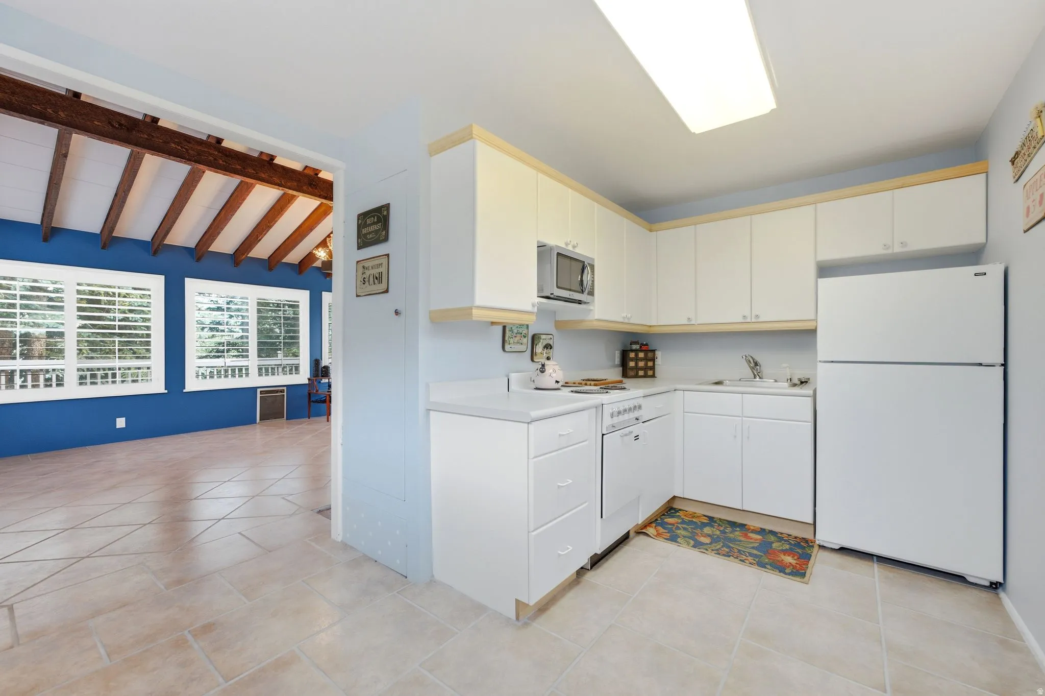L-shaped kitchen featuring white cabinetry, light countertops, and integrated appliances