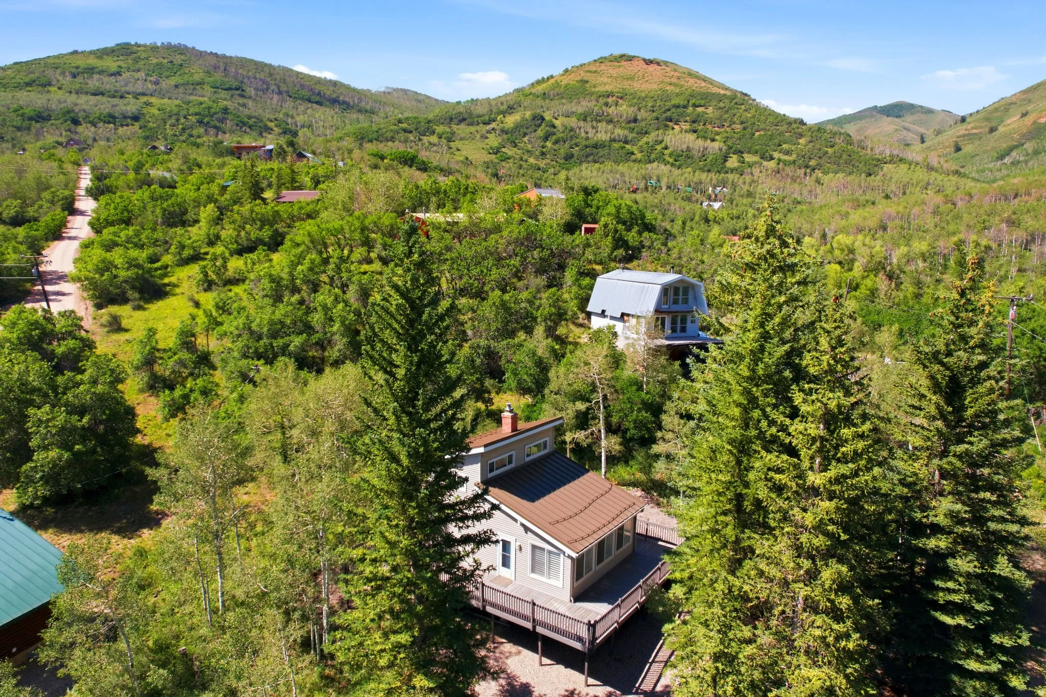 Property situated on a hillside with an expansive deck and surrounding natural landscape