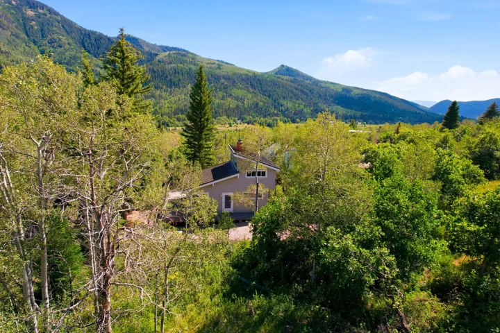 Property surrounded by mature trees with a mountain backdrop
