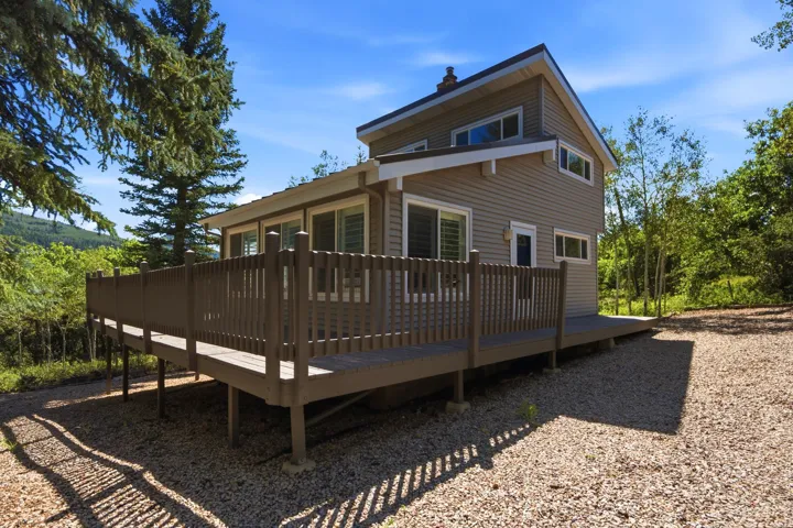 Elevated wood-finish deck surrounding a two-story residence with horizontal siding