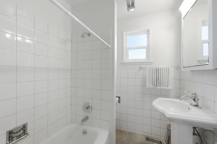 Bathroom featuring a pedestal sink with chrome fixtures, a mirrored medicine cabinet, and a window for natural light