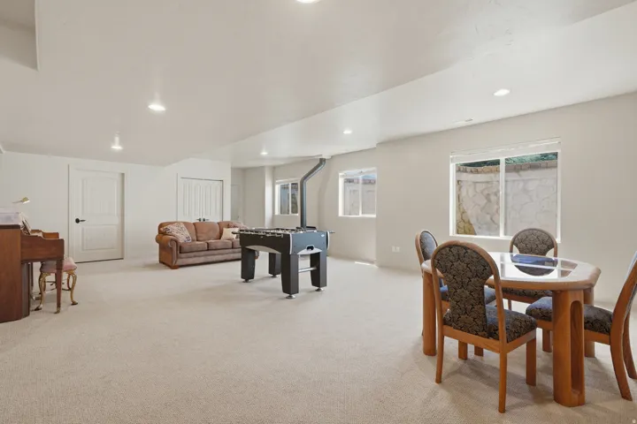 Spacious lower-level room featuring light-toned carpeting, recessed lighting, and multiple windows with white blinds