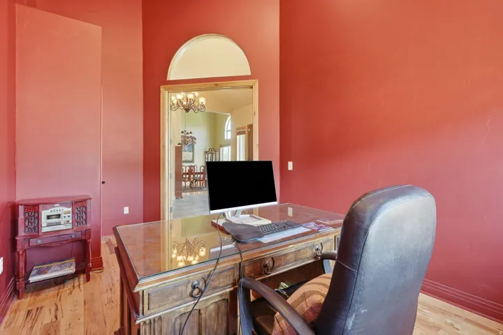 Room featuring wood-finish flooring, a decorative arched doorway with an overhead transom window, and a built-in wall panel