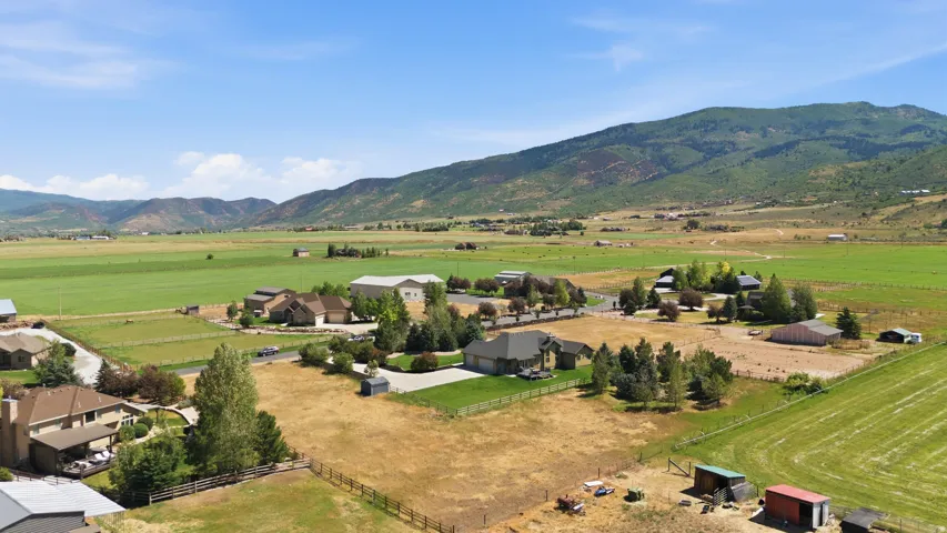 Expansive property featuring multiple structures, open fields, and mountain backdrops
