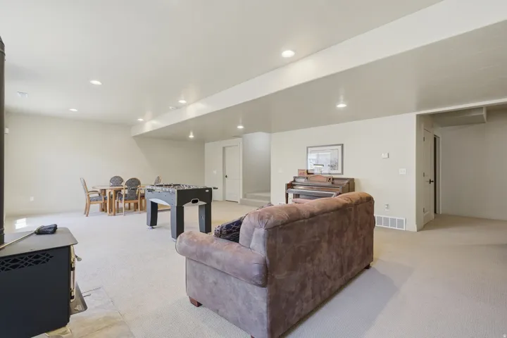 Spacious lower-level area with carpet flooring, recessed lighting, and a black wood-burning stove