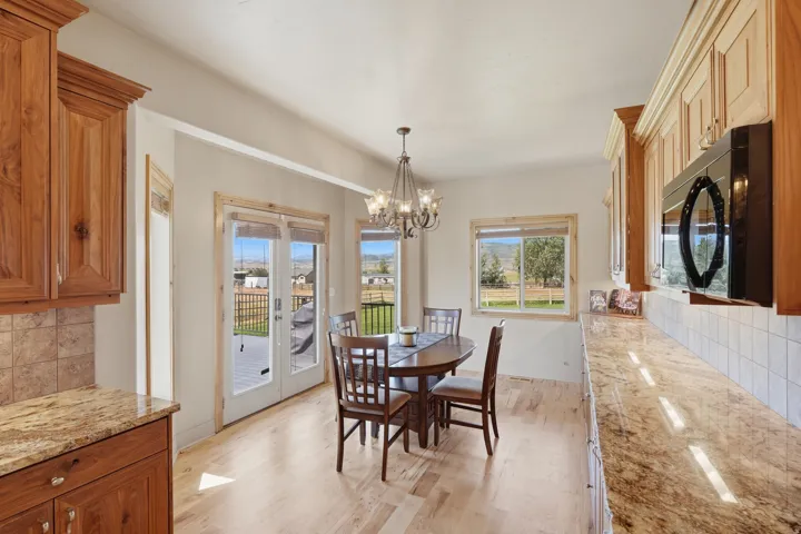 Kitchen dining area featuring wood-finish flooring, wood cabinetry, stone countertops, and a tile backsplash