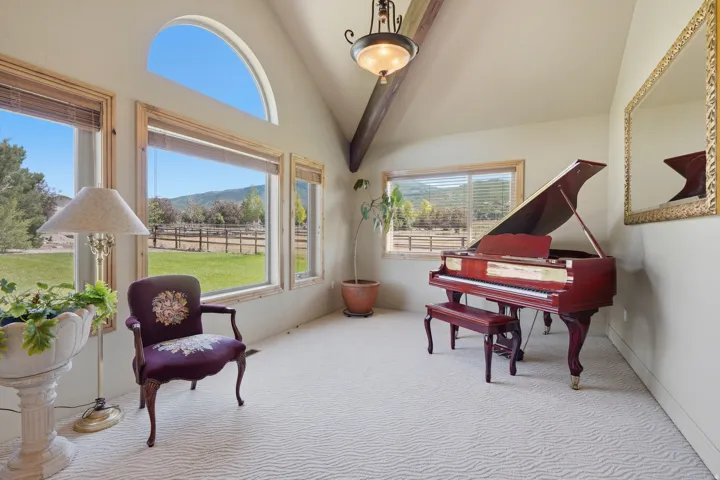 Vaulted ceiling featuring an exposed beam and an ornate chandelier