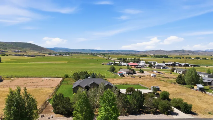 Expansive rural landscape featuring a single-family residence with a dark roof