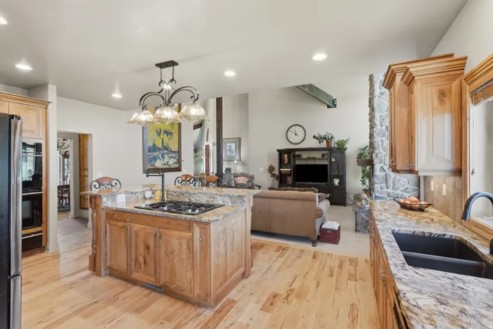 Kitchen island with a built-in gas cooktop, natural wood cabinetry, recessed lighting, and granite countertops