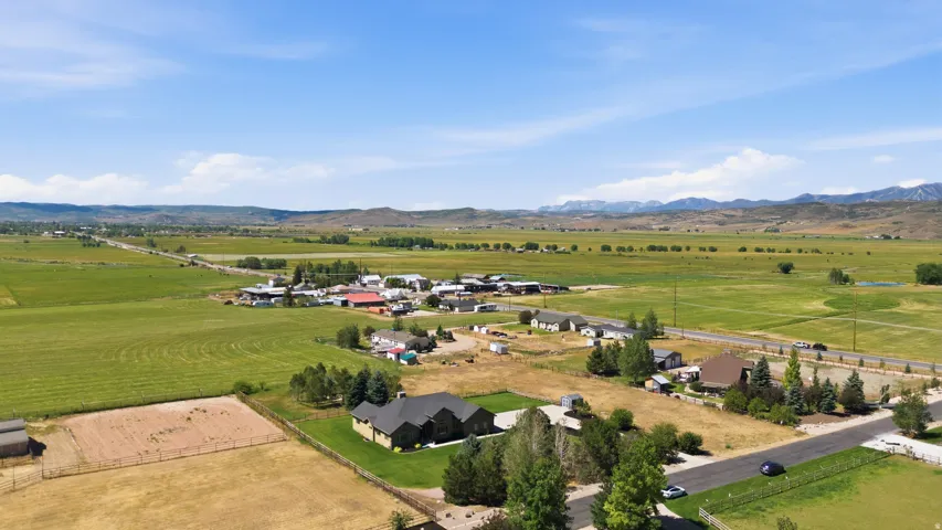 Expansive rural setting with a residential street, green fields, and distant mountains