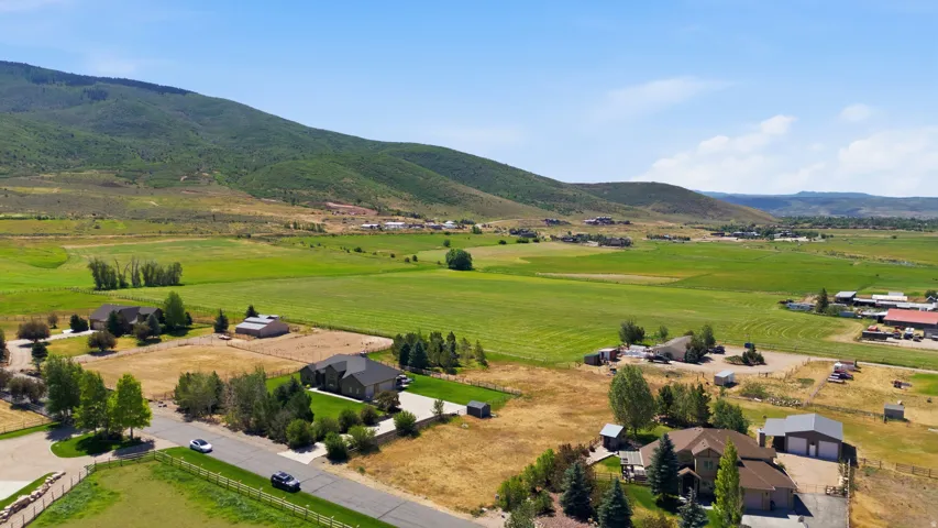 Expansive rural landscape featuring a single-story dwelling, surrounding green fields, and distant mountains