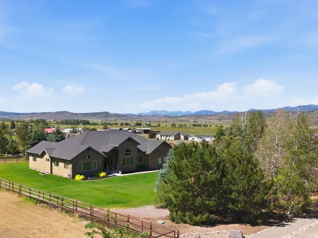 Expansive ranch-style residence featuring a dark shingle roof and a stone facade
