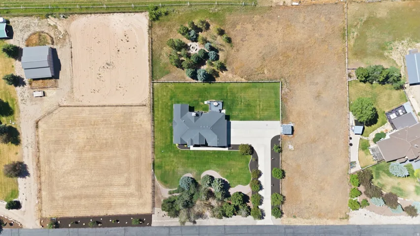 Spacious property featuring a prominent residence with a dark-shingled roof, extensive green lawn surrounding the home, a paved driveway, and mature landscaping