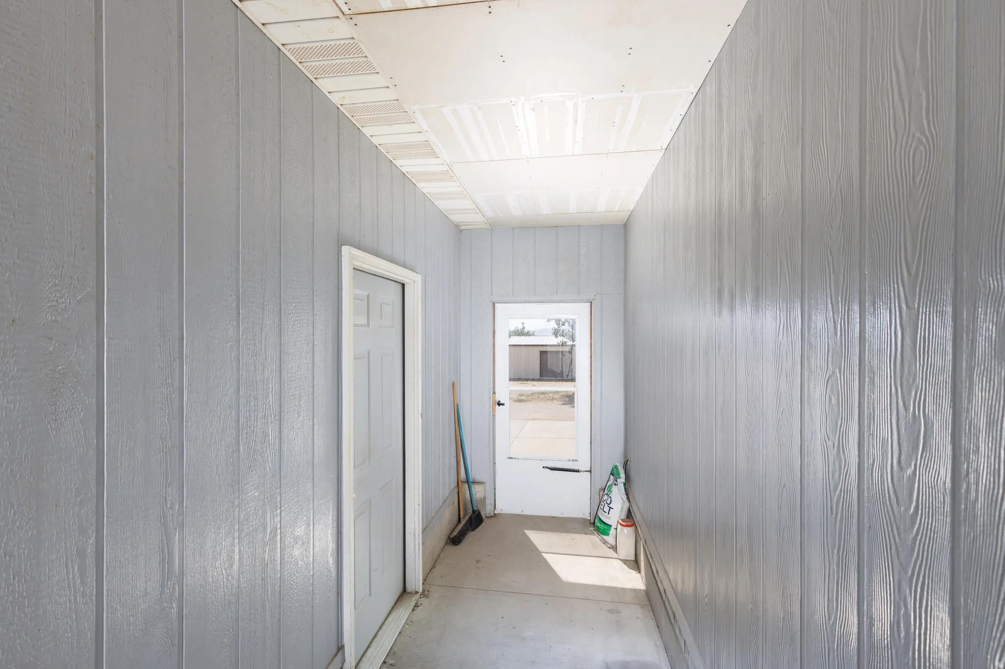 Enclosed hallway with light gray vertical paneling and a white interior door