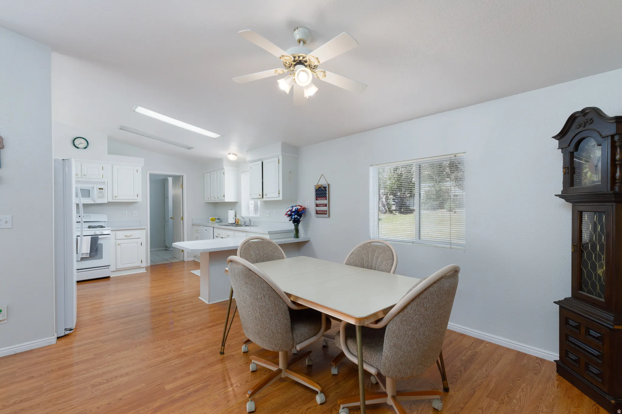Open concept dining area featuring wood-finish flooring, a ceiling fan, and a window with exterior views
