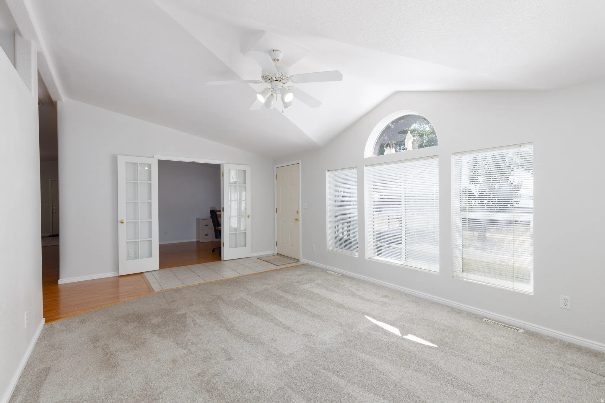 Spacious room featuring a vaulted ceiling and a ceiling fan