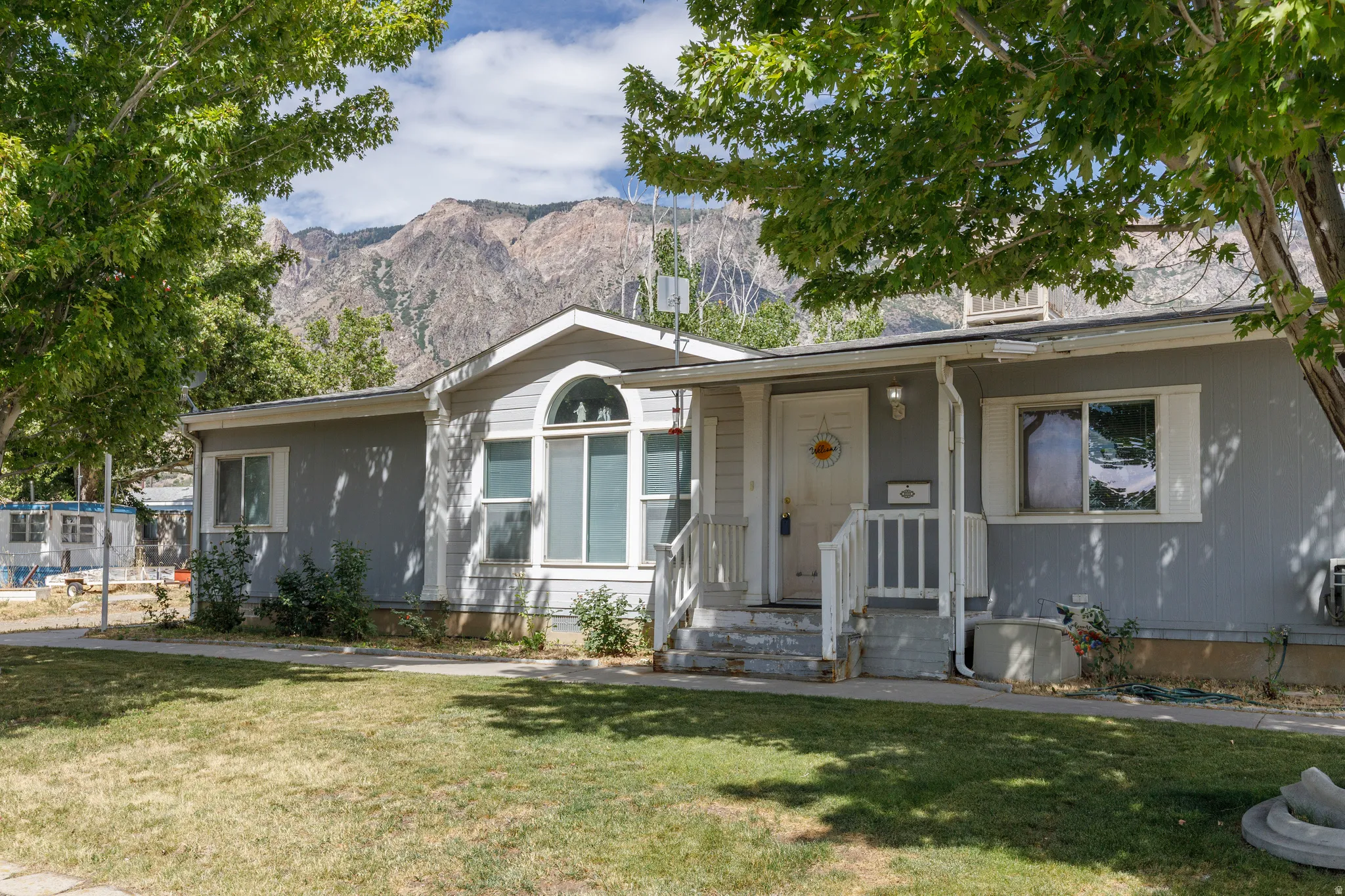 Single-story residence featuring a covered front porch with white railing, a prominent arched window, and gray exterior siding