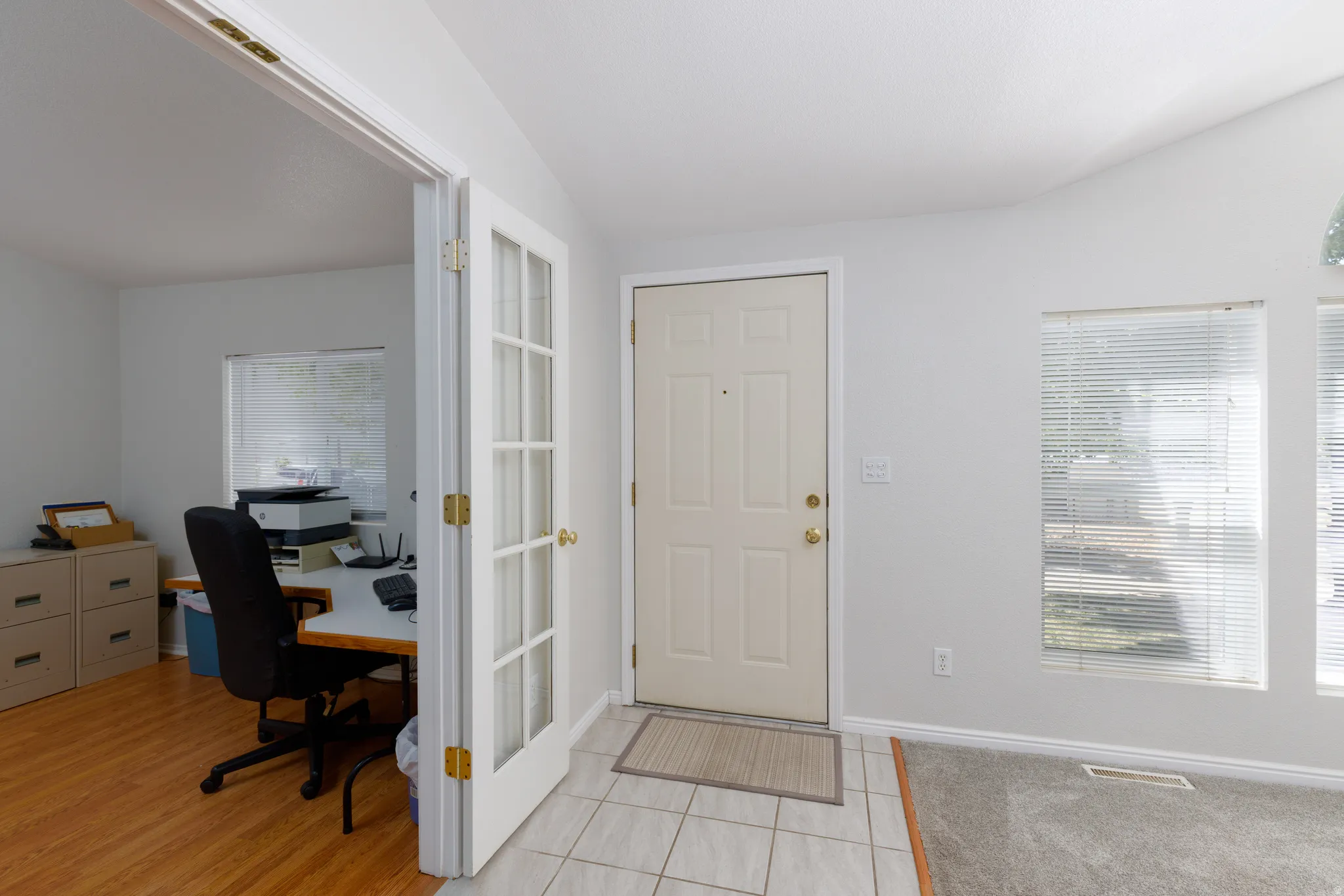 Entryway featuring tile flooring, a solid panel entry door, and two large windows with blinds