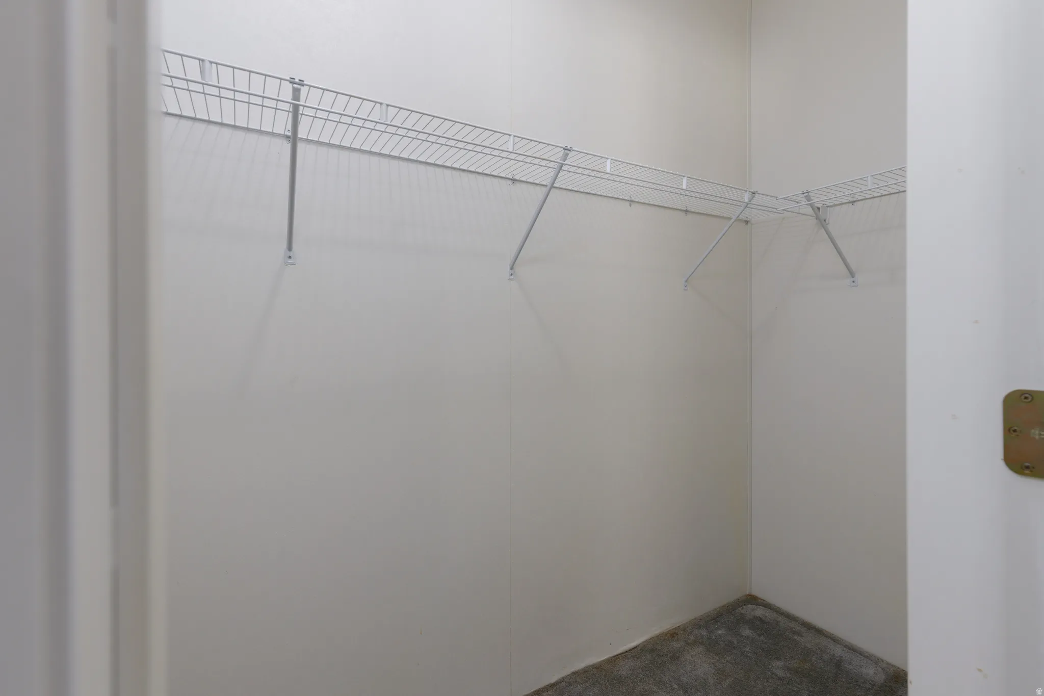Walk-in closet featuring white wire shelving and a textured floor