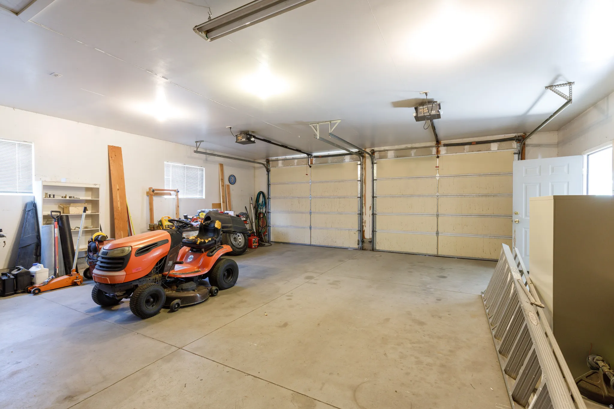 Spacious garage featuring a concrete floor, two garage doors, and built-in shelving