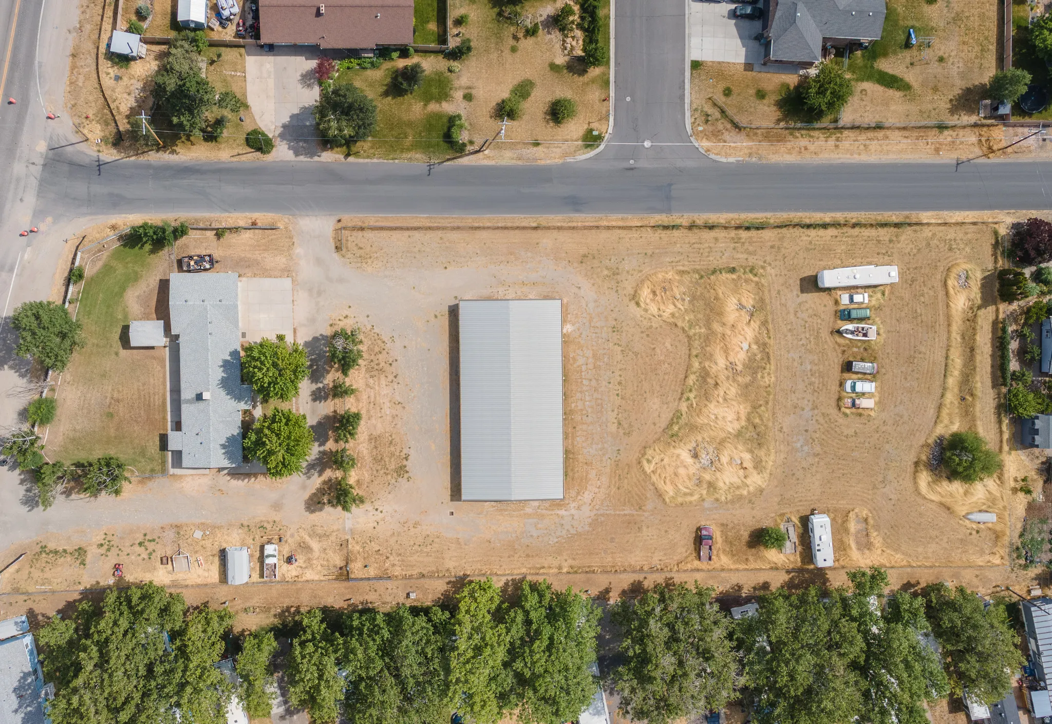 Aerial perspective showcasing a single-story residence, a large metal outbuilding, and extensive open land