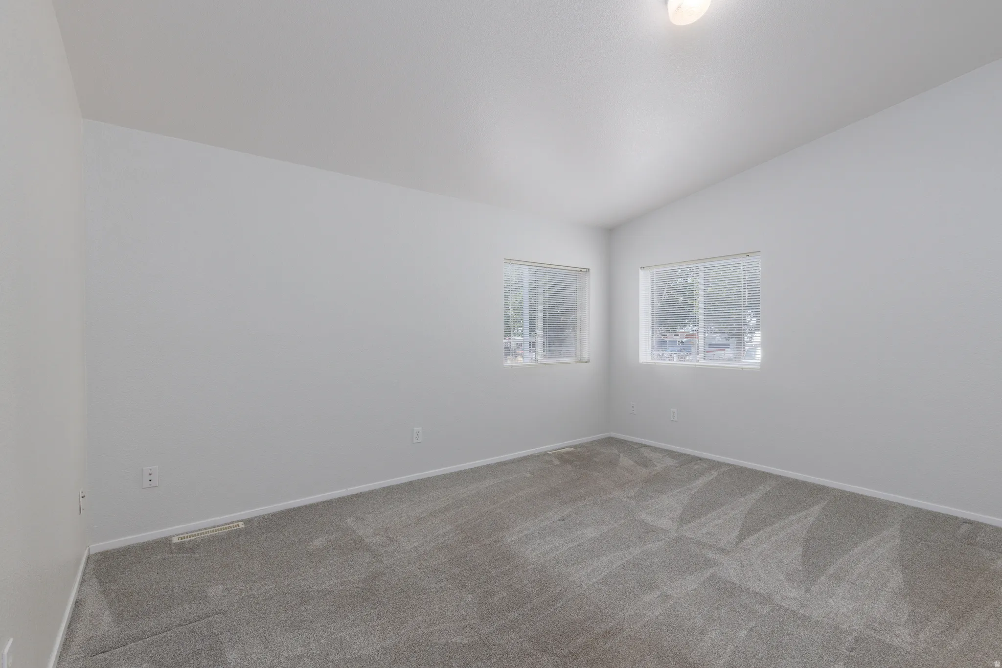 Room featuring two windows providing natural light, neutral-toned walls, and a light gray carpet