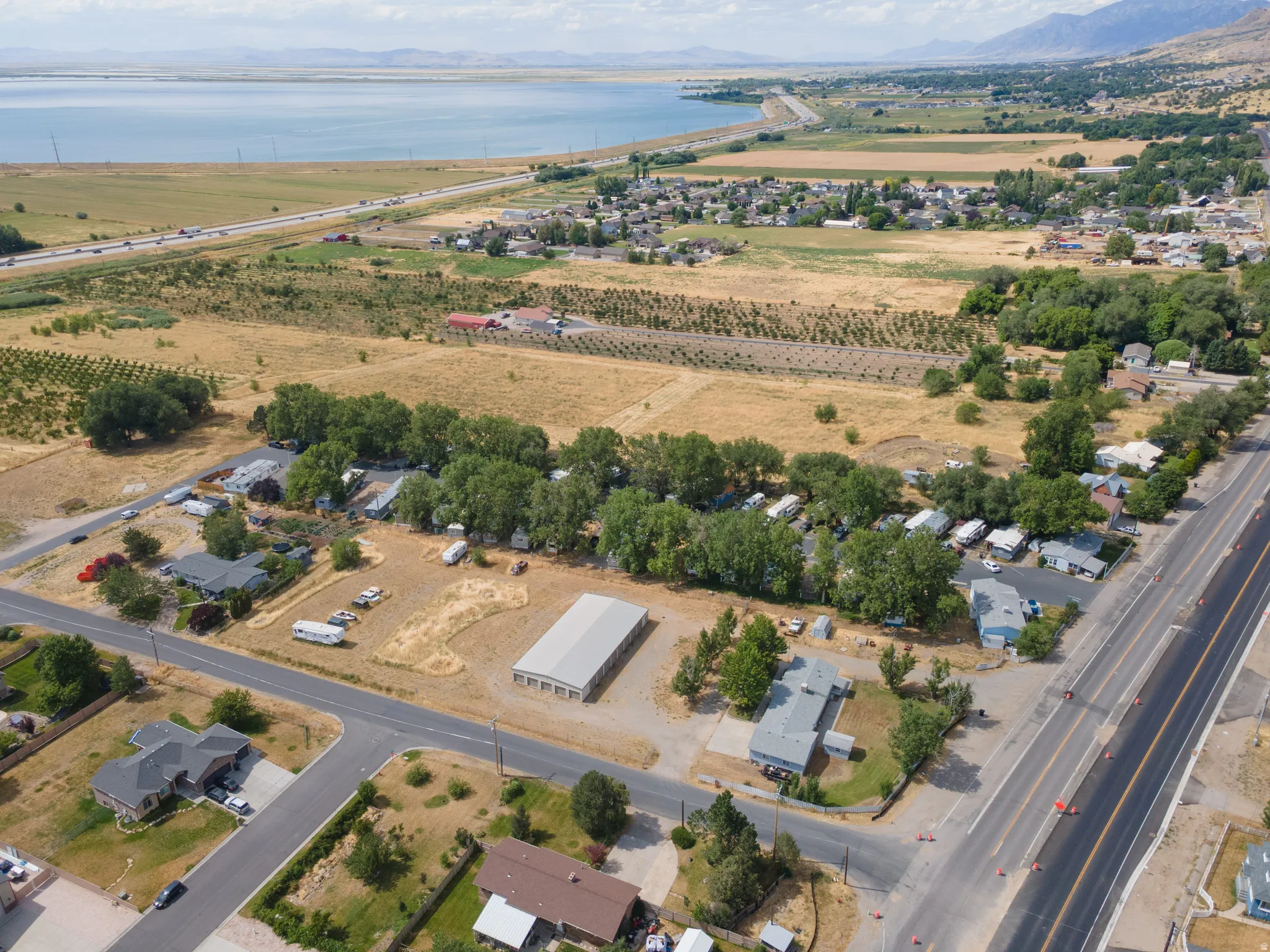 Aerial perspective showcasing multiple residential structures, an open field, and distant water body