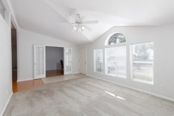 Spacious room featuring a vaulted ceiling and a ceiling fan