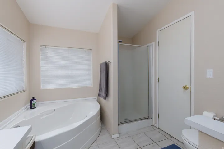 Bathroom featuring a corner soaking tub, a separate shower enclosure with frosted glass, and tile flooring