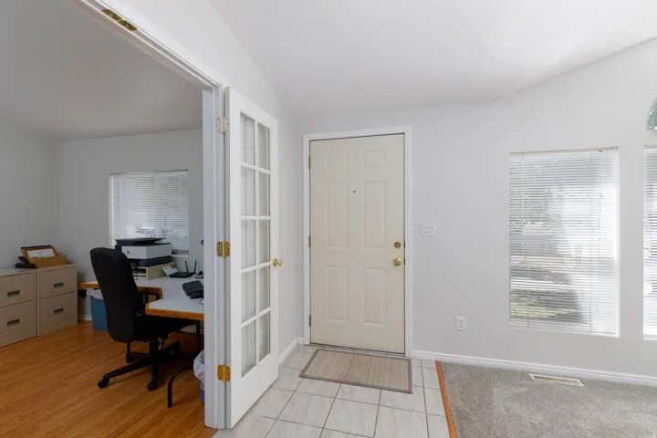 Entryway featuring tile flooring, a solid panel entry door, and two large windows with blinds