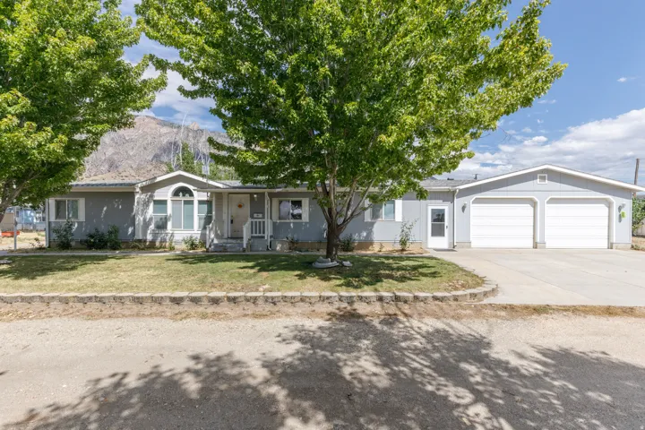 Gray-sided ranch home featuring a prominent two-car garage with white doors, a front porch with white railing, and an arched window over the main entry