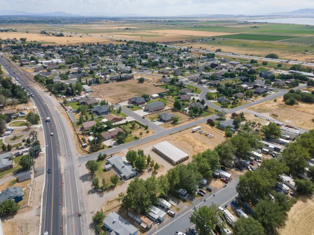 Aerial perspective showcasing a residential community with diverse housing styles, bordered by an active roadway and open fields