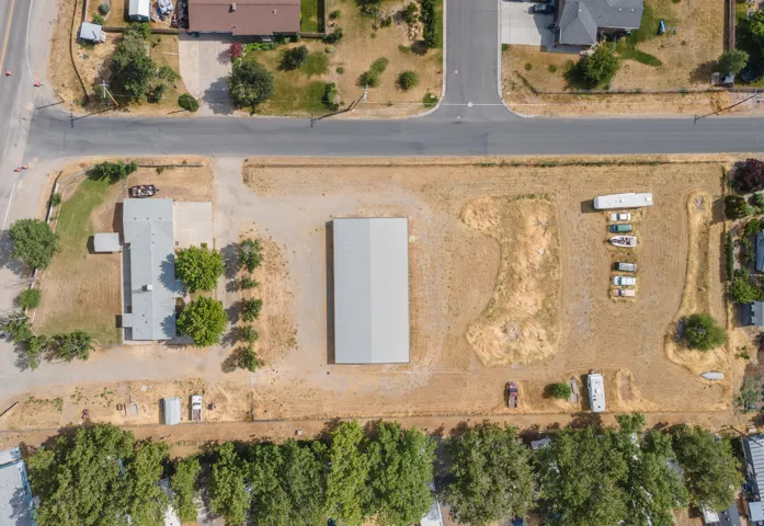 Aerial perspective showcasing a single-story residence, a large metal outbuilding, and extensive open land
