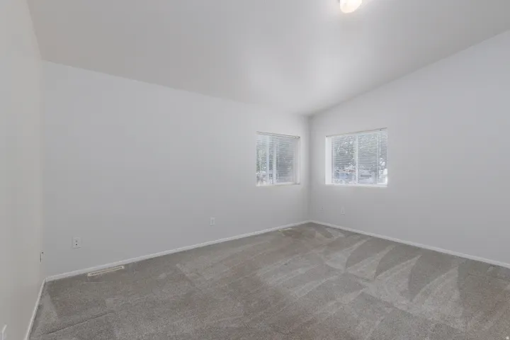 Room featuring two windows providing natural light, neutral-toned walls, and a light gray carpet