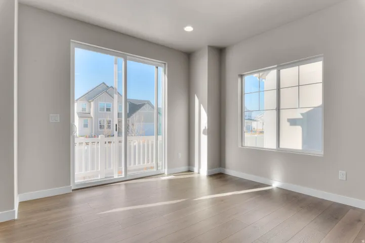 Spacious room featuring wood-finish flooring, light neutral wall tones, and white trim