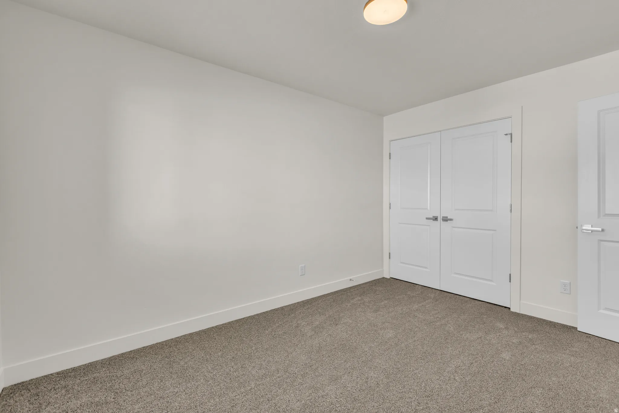 Neutral-toned room featuring a flush-mount ceiling light and wall-to-wall carpeting