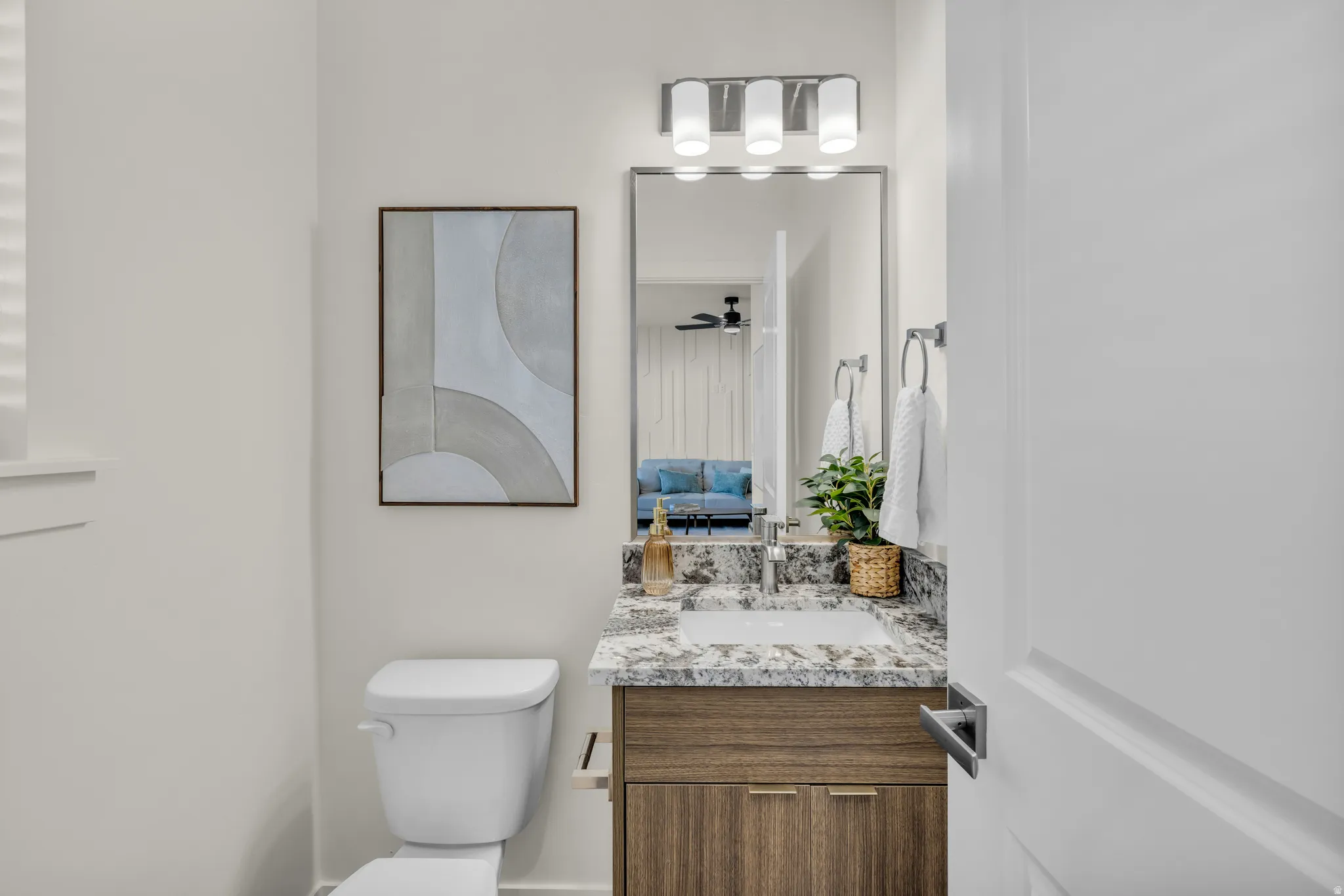 Modern bathroom vanity featuring a granite countertop with an integrated sink, wood-finish cabinetry, and a chrome faucet