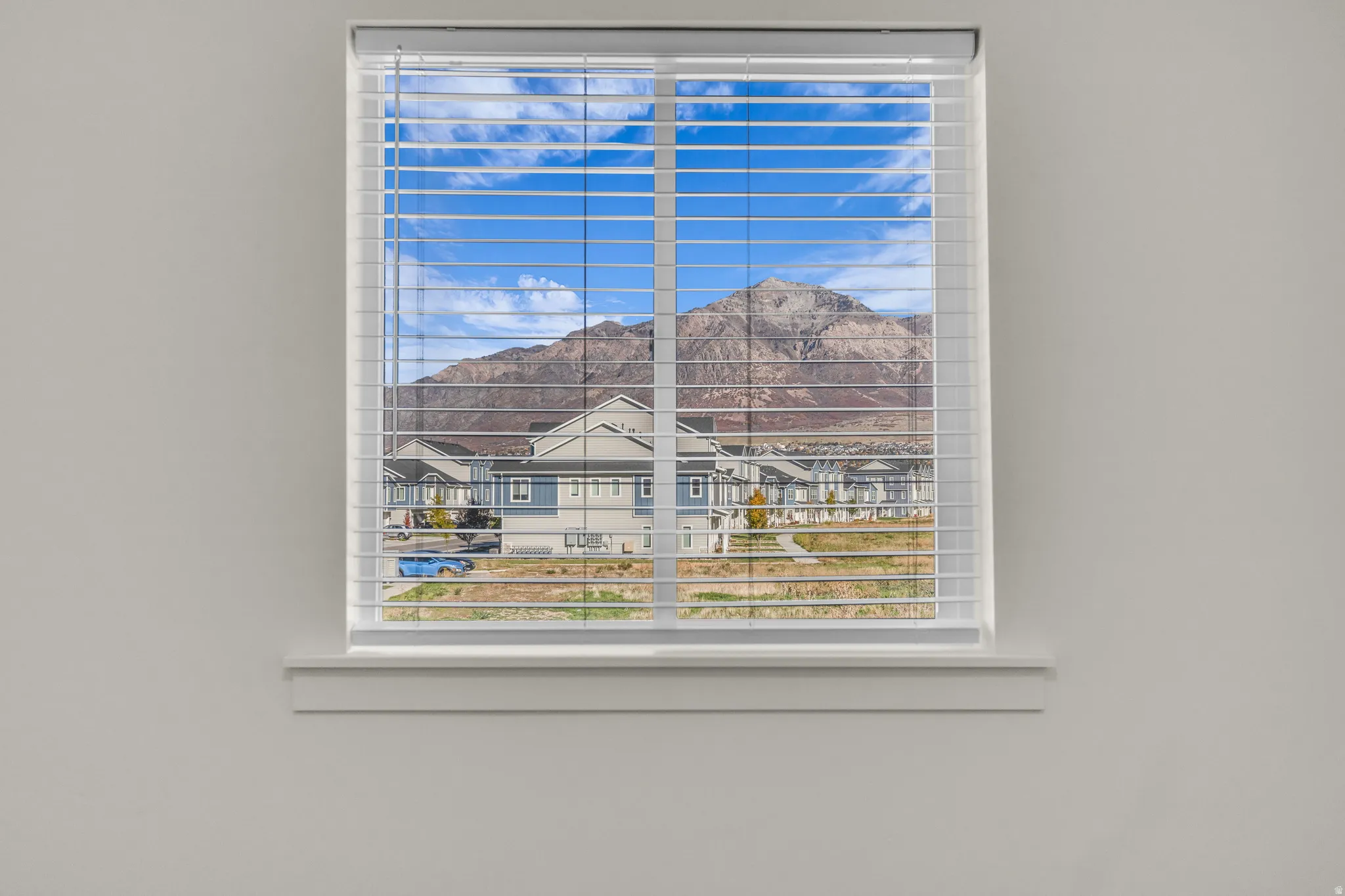 Window featuring white blinds and a mountain backdrop