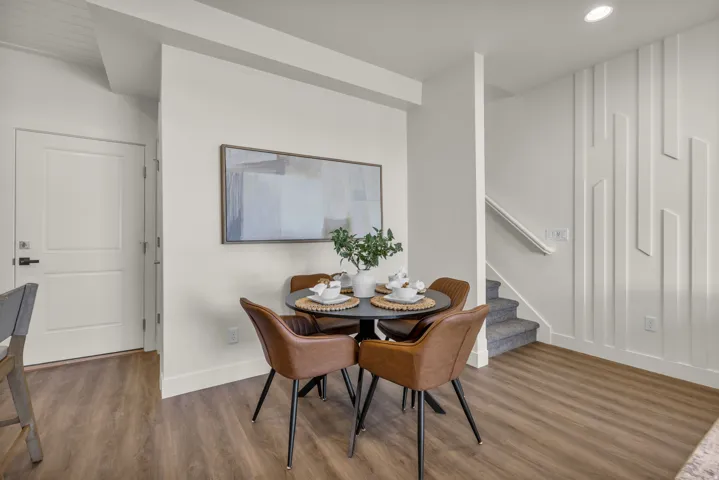 Spacious room featuring wood-finish flooring, a contemporary accent wall, recessed lighting, and a white paneled door