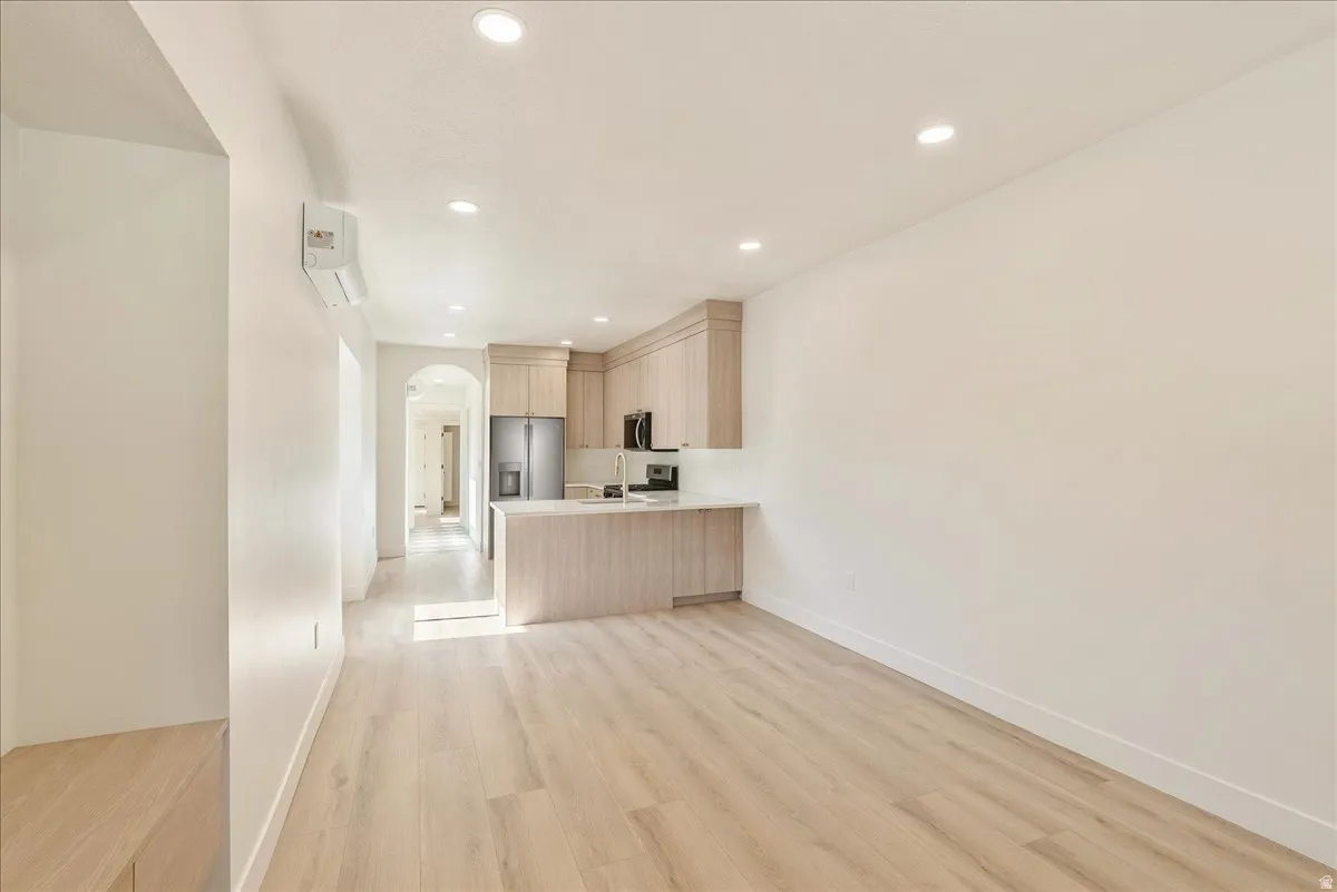 Open-concept kitchen and living area featuring wood-finish flooring, recessed lighting, and a kitchen island with a light-toned countertop