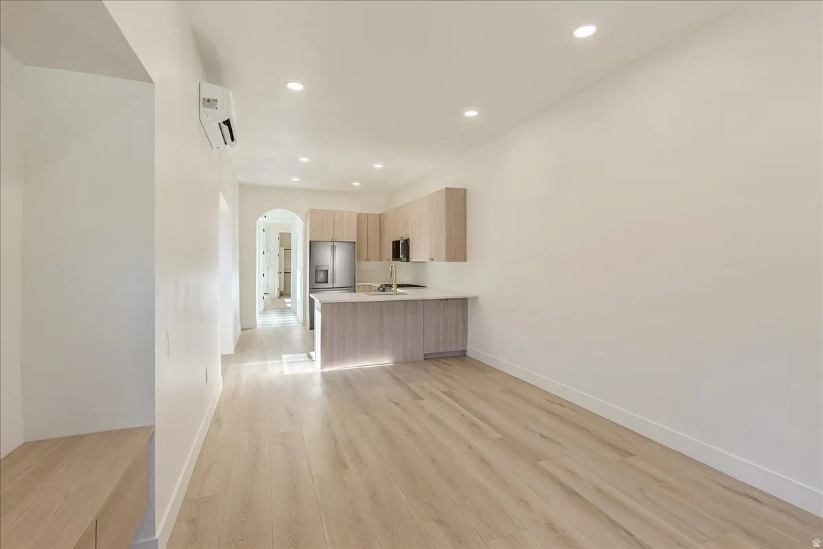 Open-concept living space featuring wood-finish flooring, recessed lighting, and a modern kitchen